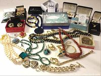 Wide view of entire jewelry lot showing variety of necklaces, earrings, bracelets, and boxed jewelry pieces.