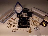 Multiple 14K gold bracelets, necklaces, pendants and earrings arranged on table