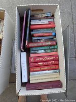 Top view of a filled cardboard box showing stacked books with visible titles including fiction and thrillers.