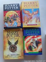 Top view of 4 Harry Potter books: Deathly Hallows, Order of the Phoenix, Cursed Child, Half-Blood Prince, all with illustrated covers.