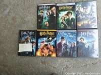Seven Harry Potter DVD cases laid out on the floor, showing front covers with main character artwork.