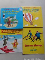 Front covers of 4 Curious George books showing title artwork, character images, and signs of light use.