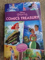 Cover photo shows the book titled 'Disney Princess Comics Treasury' featuring several Disney princesses including Cinderella, Jasmine, Ariel, Tiana, and Belle with a purple band highlighting 800 pages of magical adventures.