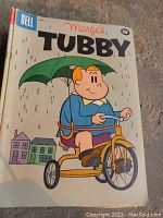 Photo of the front cover of Marge's Tubby comic book showing a boy on a tricycle under an umbrella in the rain, published by Dell, priced 15 cents.