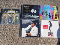 Five CDs arranged on ground: four Michael Jackson albums and one Jackson 5 album.