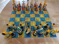 Top-down view of the full chess set laid out on a table showing all chess pieces and the patterned board.