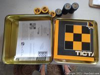 Metal tin box open showing yellow and black printed checkerboard on inside lid and cylindrical game pieces with NHL logos inside the box along with instruction sheet