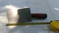 Photo of Mastercraft drywall tap knife with metal blade, taped measurement beside showing length approximately 7 inches.