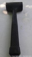 Full view of used black rubber hammer showing rubber head and textured grip handle.