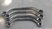 Four curved box-end wrenches laid out parallel on flat surface, sizes 8mm to 19mm.
