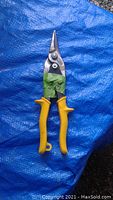 Photo of a single pair of yellow-handled 10 inch tin snips resting on a blue tarp background showing the condition and design of the tool.