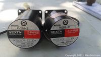 Photo of two Vexta PH268-21 2-phase stepping motors side by side on a surface, both black with red and white labels indicating model and electrical specs.