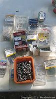 Photo showing various screws, bolts, nails in original open boxes and bags on a flat surface.