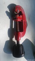 Photo showing the Mastercraft pipe cutter with red metal body, screw adjustment with black plastic knob, and cutting wheels visible.