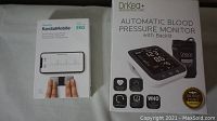 Photo of boxed AliveCor KardiaMobile EKG device and boxed Drkea automatic blood pressure monitor with packaging and product images
