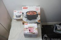 Photo of three boxed items on table: Dash mini skillet, pink rice cooker, and egg cooker