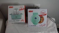 Photo showing both items in their original boxes: Dash Express Egg Cooker and Dash Mini Pie Maker in teal color.
