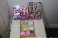 Lot displayed on white cloth with two boxed dolls and one boxed clothing accessory set.