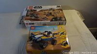 Two LEGO sets shown on table including a LEGO Star Wars desert-themed set and a LEGO Creator 3-in-1 off-road vehicle set.