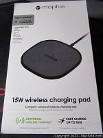Photo of Mophie 15W wireless charging pad in sealed retail box, showing compatible devices and charging specs on front.