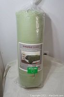 Image showing the rolled and packaged green down alternative comforter with Wayfair Basics label and King size indication.