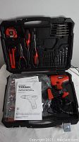 Open carrying case showing cordless drill, drill bits, screwdrivers, pliers, tape measure, power cord and user manual neatly organized inside.