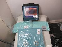 Photo showing a blue seat cover in its original packaging along with two light blue face towels on a white surface