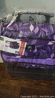 Photo of purple rolling cooler sealed in plastic showing leaf design and handle