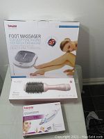 Lot containing a Beurer foot massager box, pink FlurTE hair styling brush box, and a Beurer electric personal care device box with multiple attachments.