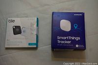 Front photo of Tile Pro 2-pack and Samsung SmartThings Tracker box on white surface.