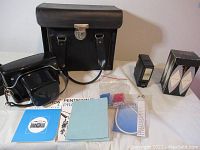 Photo of complete lot including black camera bags, flash, manuals, lens, and accessories laid out on white surface.