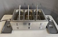 Side view of the stainless steel food warmer with all three lids in place, showing the vent design and clean condition.