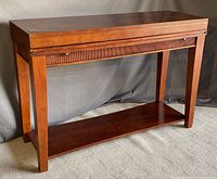 Angled front view of console with closed top, showing overall shape and finish.