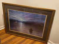 Framed print visible showing a person rowing a boat on a lake during dusk with mountains and colorful sky in background.