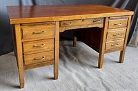 Front angle view of a large wooden desk with drawers on both sides.