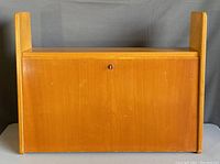 Front view of closed secretary desk showing drop-front panel and lock