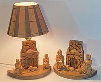 Full view of the pair showing the wooden lamp with carved figures and matching wooden carving.