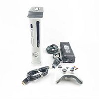 White Xbox 360 console standing vertically with front-facing disc drive, memory card slots, power button, power adapter, power cable, and HDMI cable arranged to the side.