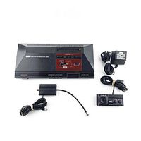 Full setup of Sega Master System console, power supply, RF adapter, and wired controller arranged on white background.