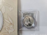 Close-up photo of the silver coin in plastic case, focusing on Bugs Bunny engraving.