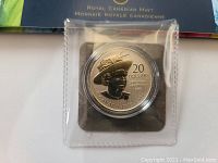 Close-up of the silver coin inside protective plastic casing showing the Queen's portrait, denomination $20, and dates 1952-2012.