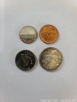 Top side of four 1967 Canadian centennial coins showing commemorative reverse designs: penny (rock dove), nickel (rabbit), dime (Bluenose schooner), quarter (polar bear).