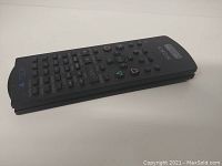 Black Sony remote control for PS2 shown from an angle showing many buttons and the PlayStation logo.