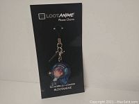 Phone charm mounted on a black Loot Anime backing card showing the front of the charm and branding text.