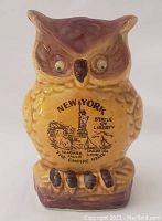 Front view of ceramic owl pepper shaker showing New York themed graphics.