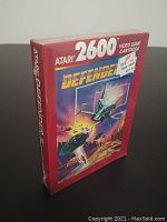 Front view of the sealed Atari 2600 Defender II cartridge box showing space battle artwork and Atari 2600 branding. Price sticker from Zeller's store attached.