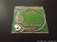 Front view of the silver-tone adjustable bracelet with three distinct themed charms on original green Plants vs Zombies card.