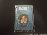 Front view of the Walking Dead Emanuel enamel pin in original packaging with BAM! backing card.