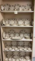 Shelf with multiple pieces of Schlaggenwald china including cups, saucers, bread plates, bowls, dinner plates and salad plates arranged neatly.