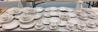 Wide angle photo showing full set of Hutschenreuther china including plates, cups, saucers, bowls, sugar bowl, and teapot arranged on table
